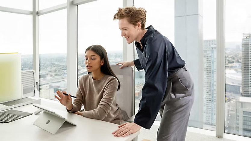 Two co-workers looking at a Surface Pro.