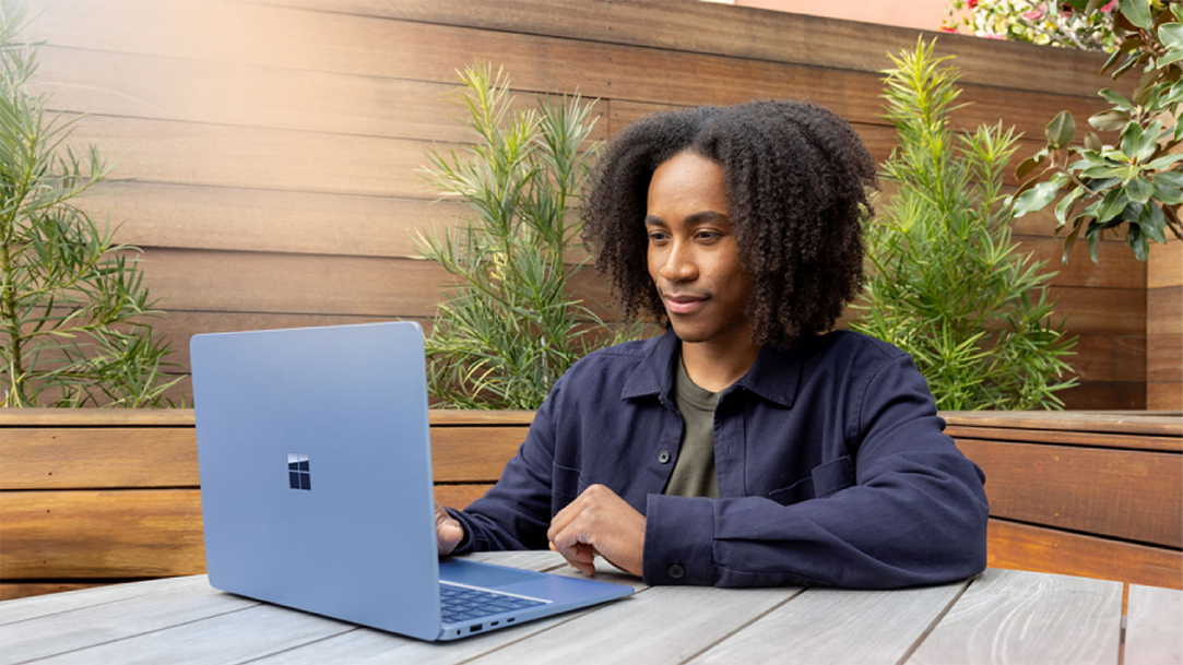 A man working on a Microsoft laptop outside