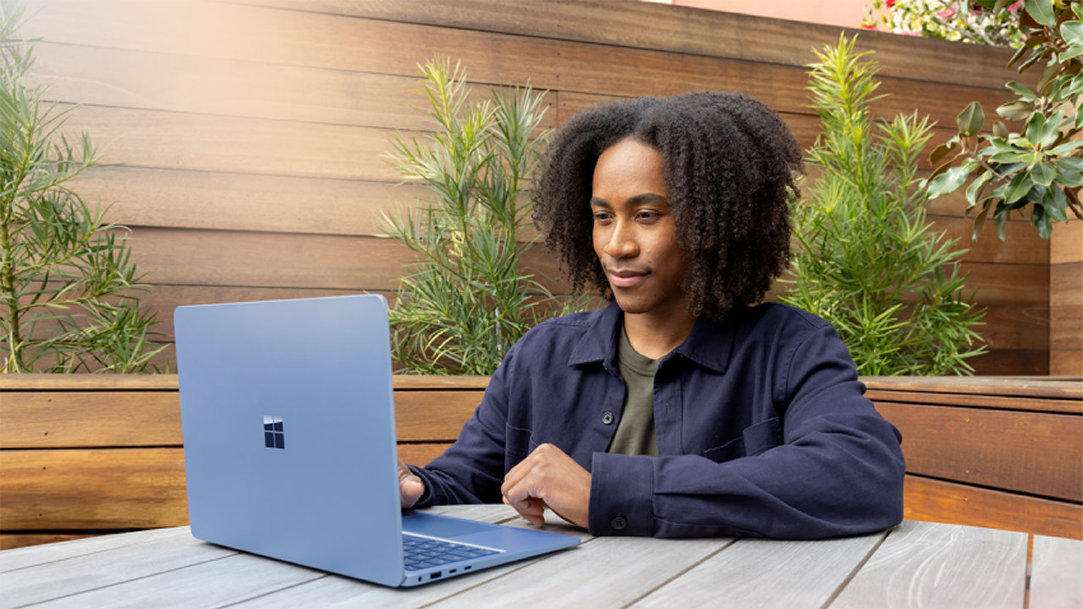 A man working on a Microsoft laptop outside