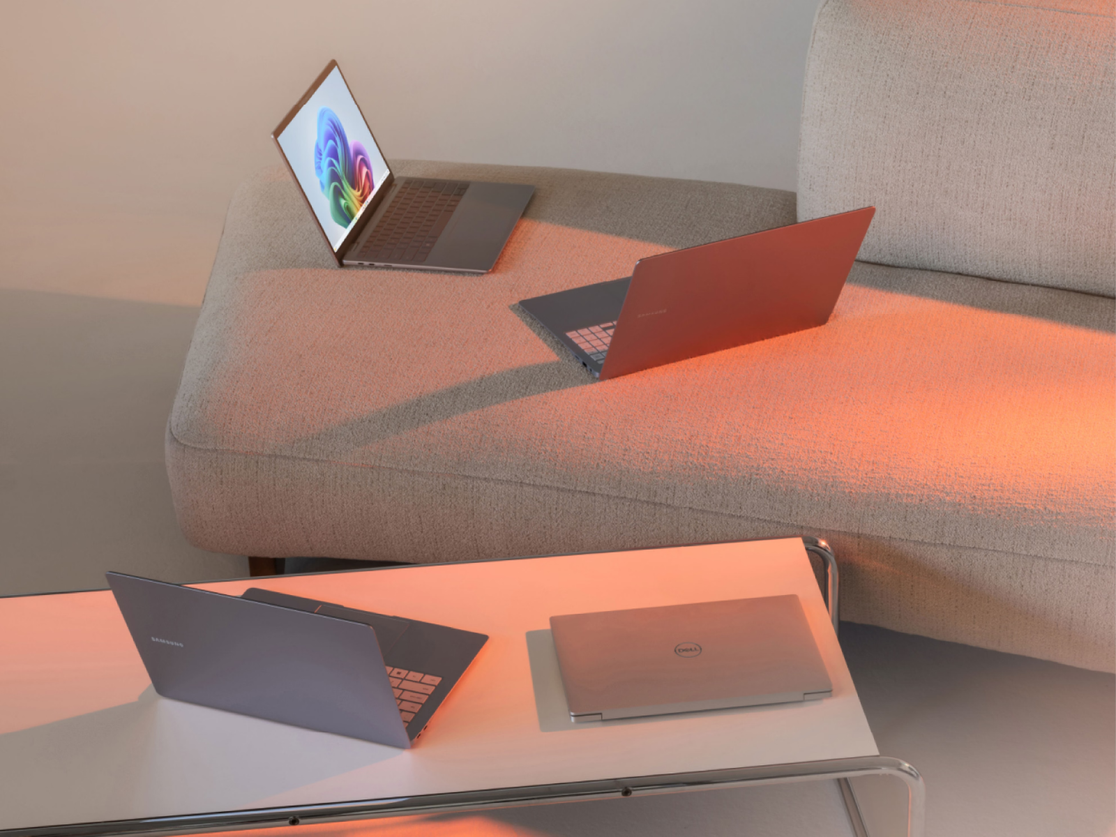 Plusieurs ordinateurs portables posés sur une table basse et un canapé