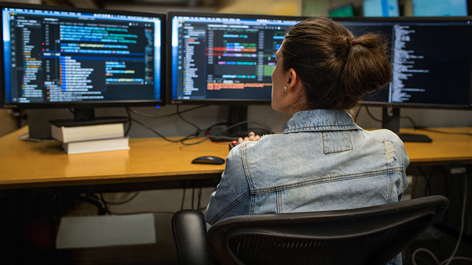 A developer uses Visual Studio to code on dual monitors.